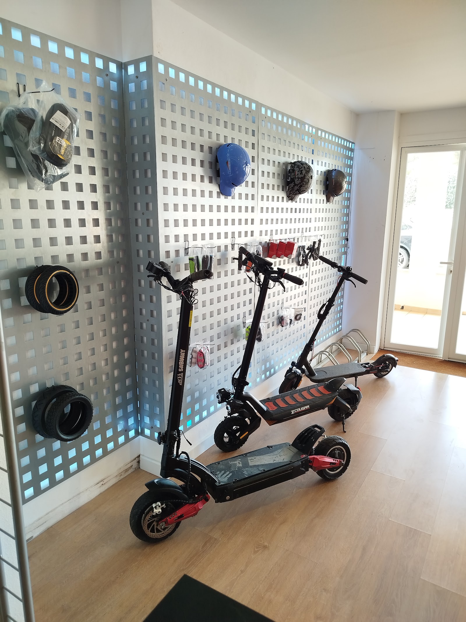 Patinetes eléctricos, cascos y neumáticos expuestos en la pared de la tienda